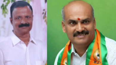 BJP Belur MLA and another man in white shirt, both smiling, in a formal setting.