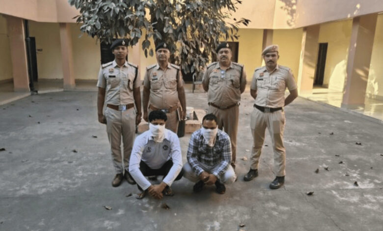 Six men, some in police uniforms, pose outdoors with two kneeling men wearing masks.