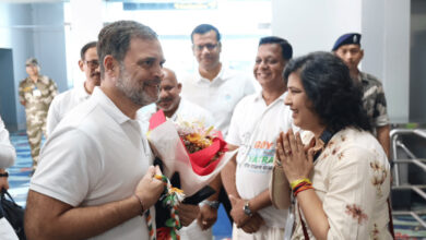 Man presenting flowers to woman in a welcoming gesture at an indoor event.