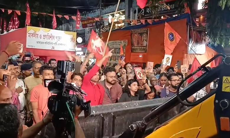 Crowd of protesters with flags and banners during a political rally at night.