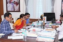 Business meeting with five people discussing documents in a modern office.