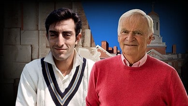 Two men, a young and an elderly, standing outdoors with a historic building in the background.