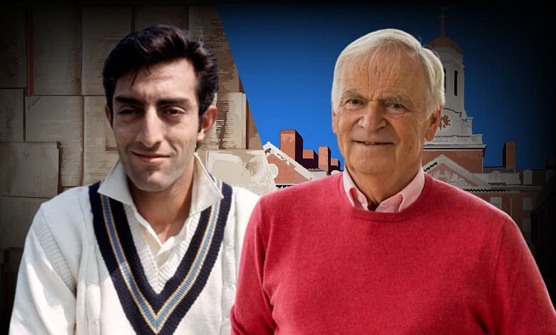 Two men, a young and an elderly, standing outdoors with a historic building in the background.