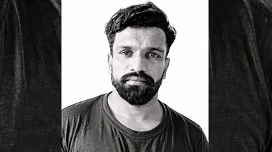 Black and white portrait of a man with a beard and short hair, wearing a dark t-shirt.