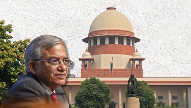 Supreme Court of India with a senior official in front, clear sky, and greenery.