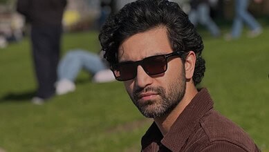 Pakistani actor Ahad Raza Mir wearing sunglasses outdoors in a park setting.