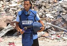 Gaza journalist Anas Al-Sharif in front of rubble after an attack.