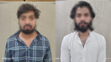 Two men with blurred faces standing against a plain background.