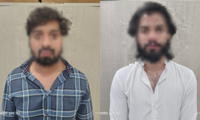 Two men with blurred faces standing against a plain background.