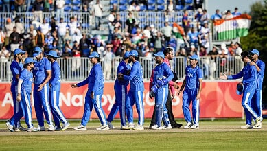 Indian cricket team players walking on the field before a match, with spectators in the background.
