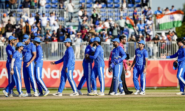 Indian cricket team players walking on the field before a match, with spectators in the background.