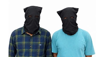 Two men wearing black masks and casual shirts, posing for the camera.