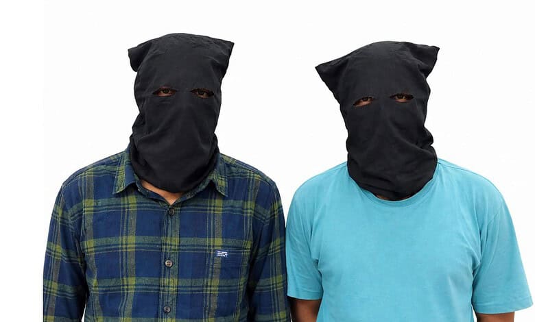 Two men wearing black masks and casual shirts, posing for the camera.