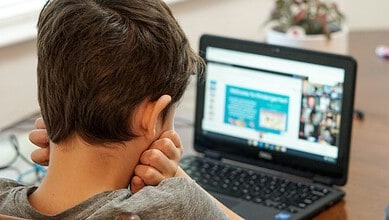 Young student engaged in online learning on a laptop at home.