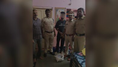 Group of men, including police officers, standing indoors with a young man in the centre.