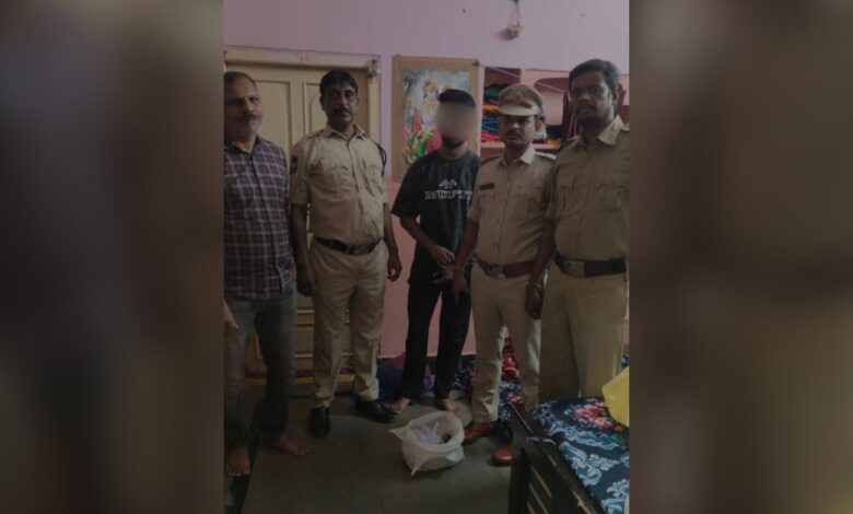 Group of men, including police officers, standing indoors with a young man in the centre.
