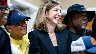 Diverse group of people smiling and engaging at a political event, highlighting veteran issues and US-Her.