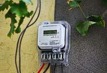 Electricity meter on a wall with green leaves nearby, showing a reading of 950716.
