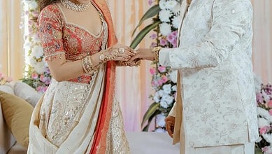 Indian couple exchanging wedding rings during traditional ceremony with floral decor.
