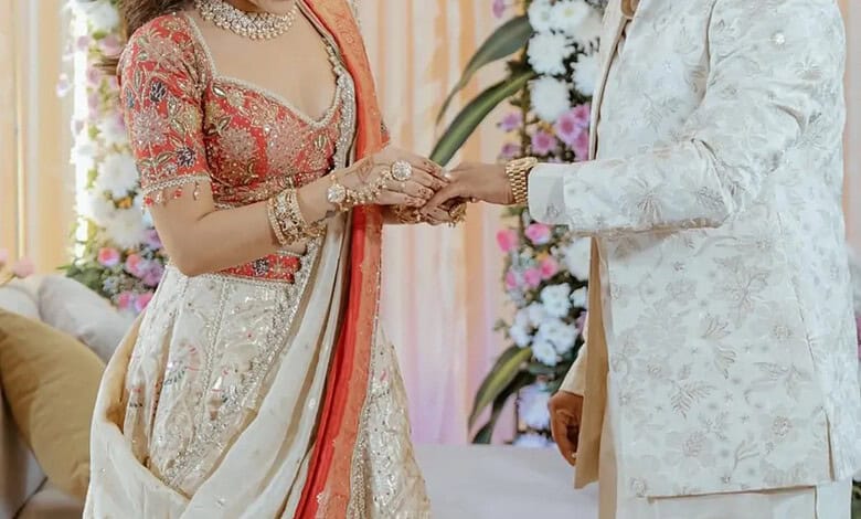 Indian couple exchanging wedding rings during traditional ceremony with floral decor.