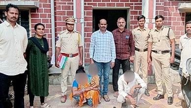 Group of police officers and individuals outside a building in Hyderabad's Dhoolpet.
