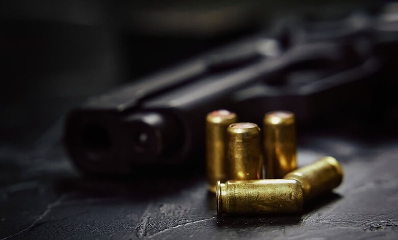 Firearm with bullets on a dark surface, related to shooting incident in Hyderabad.