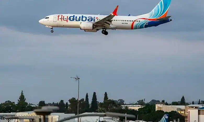 Flydubai plane flying in cloudy sky with cityscape below.