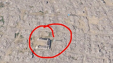 Aerial view of a building in Gaza surrounded by destruction, marked with a red circle.