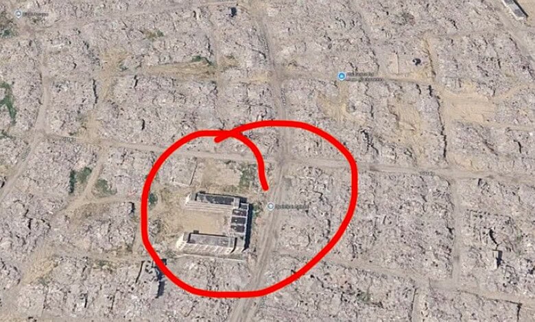 Aerial view of a building in Gaza surrounded by destruction, marked with a red circle.