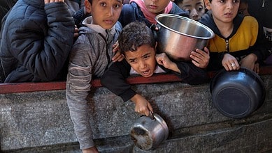Children in Gaza waiting for aid, showing signs of hunger and distress amid ongoing crisis.