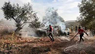 Civil Defence workers extinguish a burning vehicle beside olive trees near Turmus Ayya in the occupied West Bank.