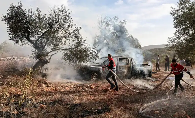 Civil Defence workers extinguish a burning vehicle beside olive trees near Turmus Ayya in the occupied West Bank.