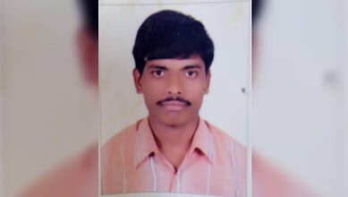 Jagtial man with black hair and mustache, wearing a pink shirt, looking at the camera.