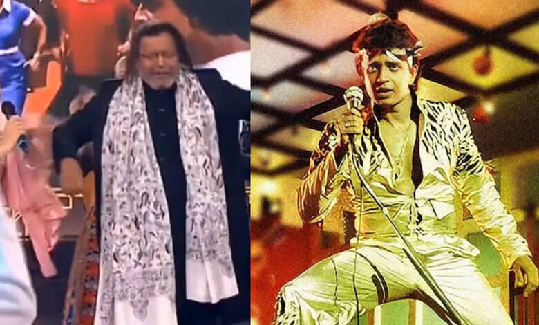 Mithun Chakraborty performing on stage in a yellow outfit with a microphone.