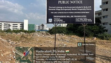 Public notice on land protection in Hyderabad, India, with city buildings in the background.