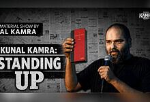 Kunal Kamra holding a red book and microphone during his stand-up show.