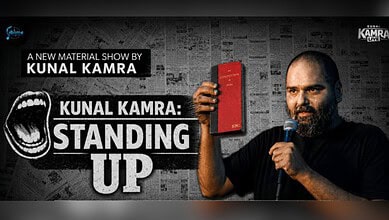 Kunal Kamra holding a red book and microphone during his stand-up show.