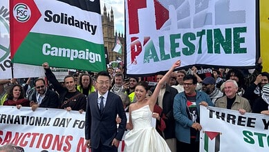 Newlywed couple poses with demonstrators holding Palestine banners in London.