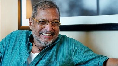 Nana Patekar smiling in a casual setting with glasses and a turquoise shirt.