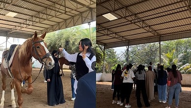 Group of people interacting with horses in an indoor equestrian facility.
