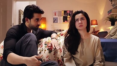 Pakistani drama scene with a man and woman in a living room setting.