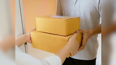 Person handing over two yellow parcels to another individual.