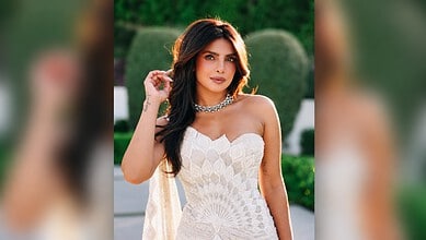 Priyanka Chopra wearing a white strapless dress with jewelry, outdoors in a garden setting.