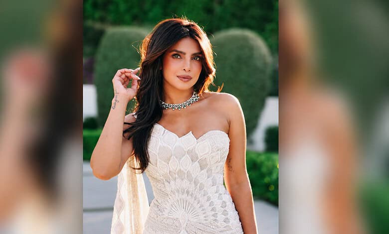Priyanka Chopra wearing a white strapless dress with jewelry, outdoors in a garden setting.