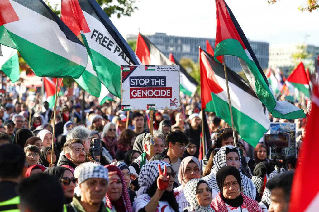 Demonstrators carry Palestinian flags and a “Stop the Genocide” sign during a pro-Palestine rally in Berlin.
