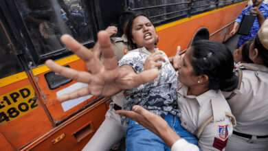 Policewoman detains woman during protests in Delhi, tense confrontation at the scene.