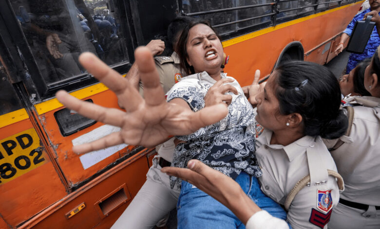Policewoman detains woman during protests in Delhi, tense confrontation at the scene.
