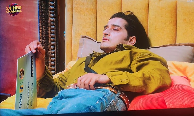 Qazi Touqeer relaxing on a bed with a book in a yellow and orange room.