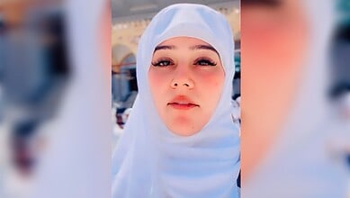 Young woman wearing white hijab with a serene expression at a religious site in Saudi Arabia.