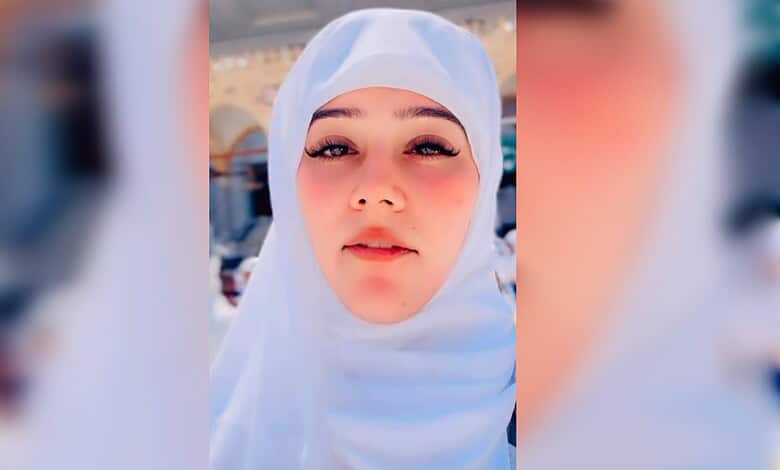 Young woman wearing white hijab with a serene expression at a religious site in Saudi Arabia.
